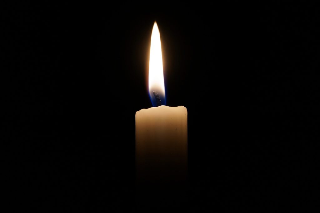 Ett ensamt stearinljus lyser i mörkret.