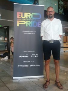 Syntolkning: Stefan står framför Europride-banderollen.