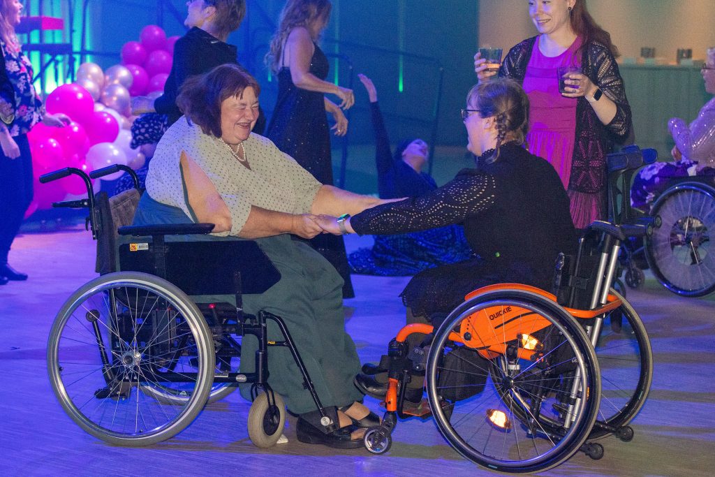På ett dansgolv buggar två kvinnor i varsin rullstol med varandra.