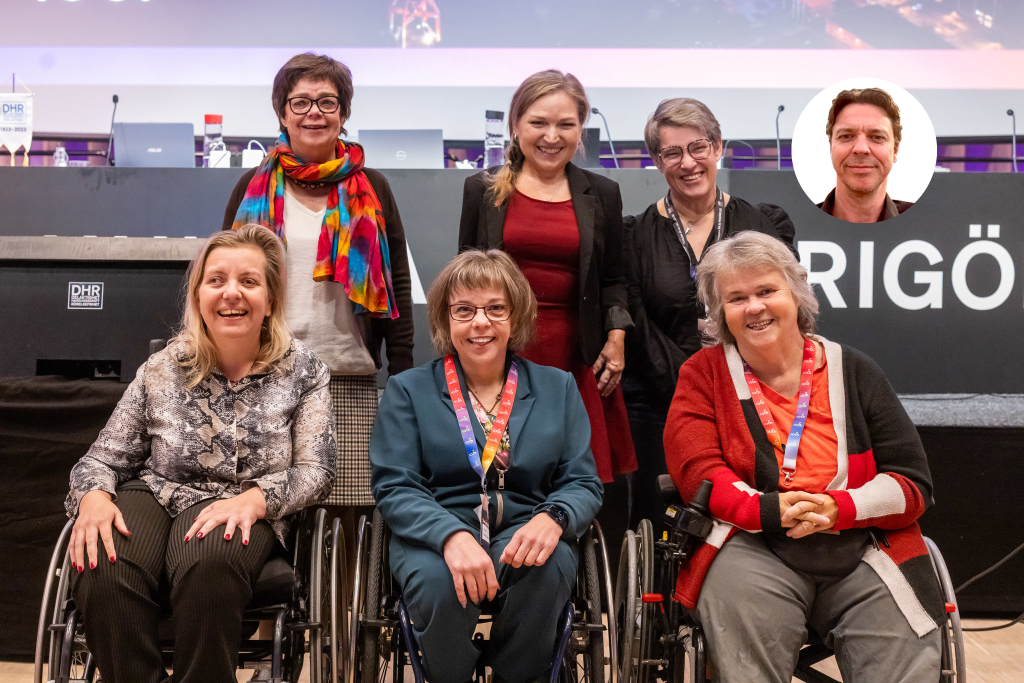 Sex kvinnor framför ett podium. Inklippt bredvid dem syns en man. Tre av kvinnorna står upp, tre sitter i rullstol.