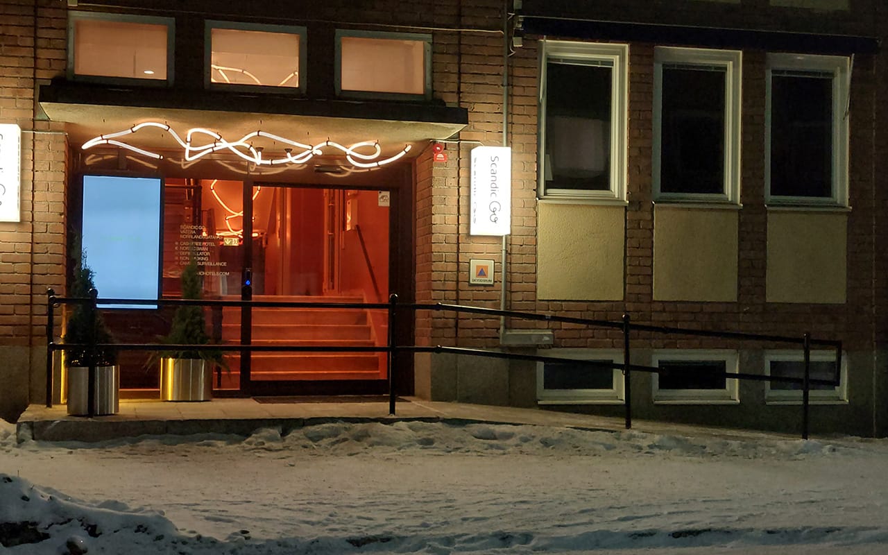 Ett hotell med ramp upp till entrén och en skylt som visar att byggnaden rymmer ett skyddsrum.