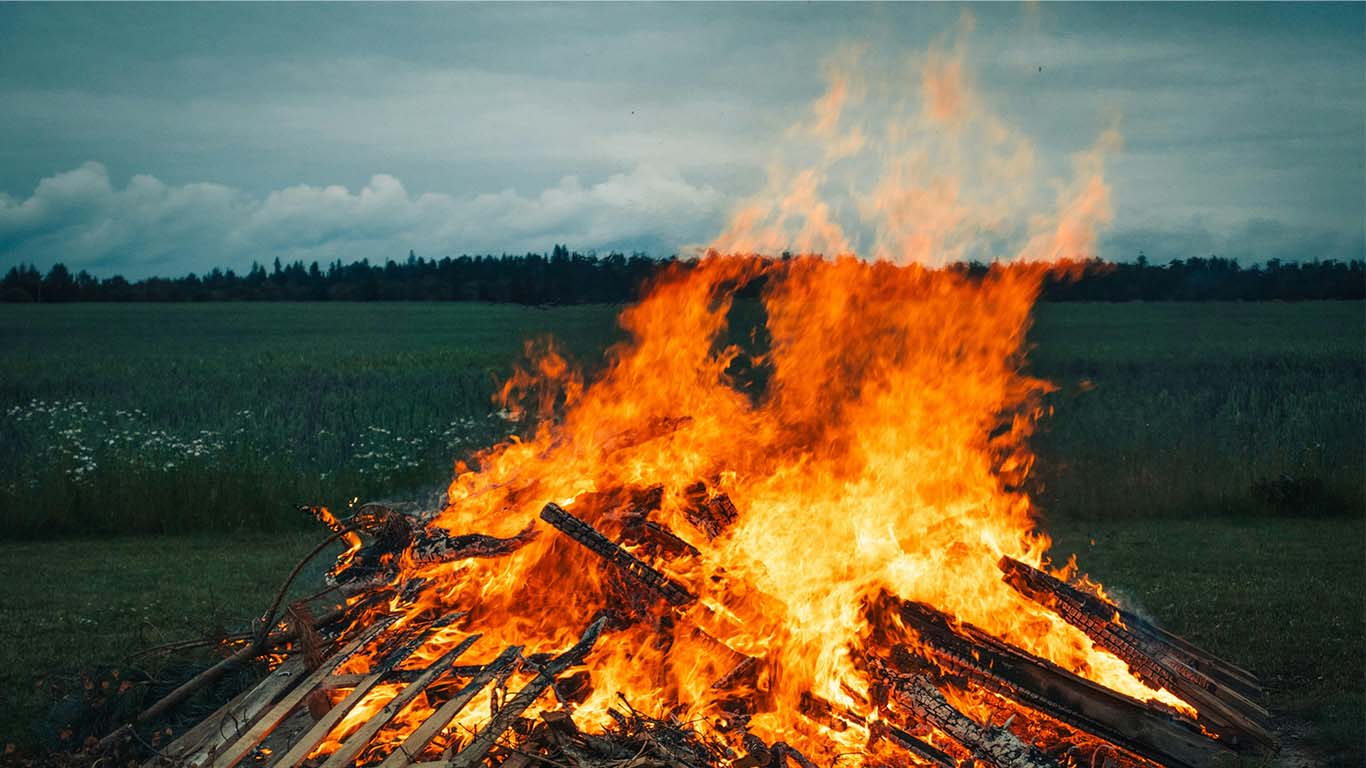 Sprakande majbrasa i kanten av en försommargrön åker.