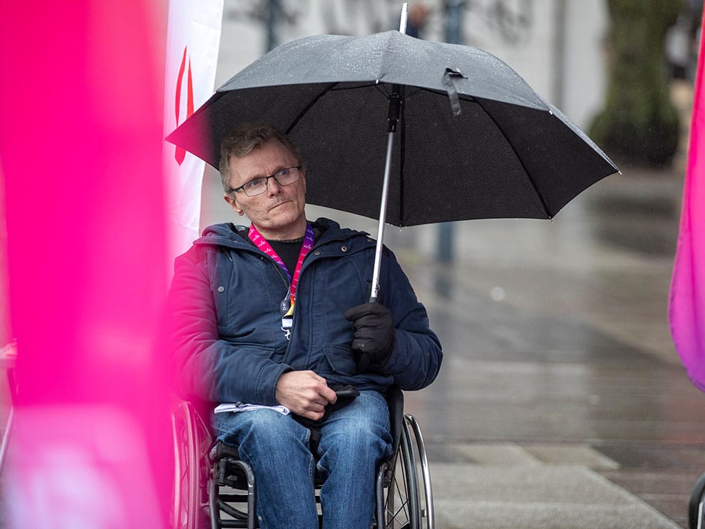 Man som söker skydd för regnet under ett paraply.